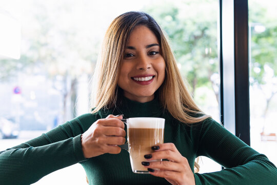 Smiling woman holding coffee mug at cafe