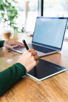 Businesswoman with laptop using graphics tablet at cafe