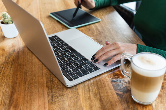 Businesswoman using laptop with graphics tablet in coffee shop