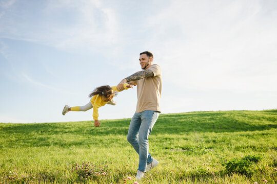 Carefree father spinning daughter on grass
