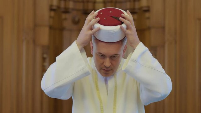 Portrait of Muslim cleric.A Muslim cleric greets the congregation who came to the mosque for Friday prayers. Muslim greeting.A Muslim cleric adjusting his clothes for Friday prayers.