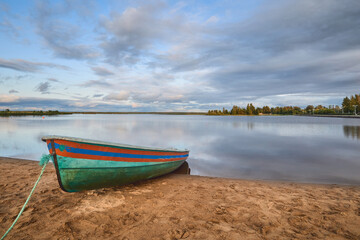 Rescue boat on the shore of the lake in calm summer weather: sandy beach, clouds, Sestroretsky Razliv.