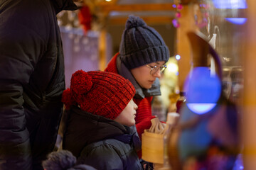 family winter holidays buying treats at christmas market in kiosk . winter shopping with kids