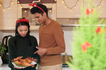 Young couple discussing fried chicken they prepared for Christmas dinner