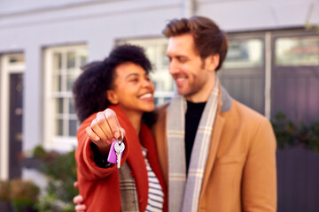 Smiling Multi Cultural Couple Outdoors On Moving Day Holding Keys To New Home In Fall Or Winter