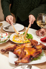 Hands of woman in warm sweater mixing delicious salad at Christmas dinner