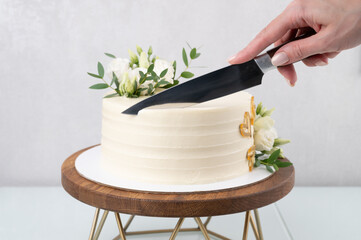 Cropped shot of woman cutting delicious cake on white background. Wedding layer cake on a wooden...