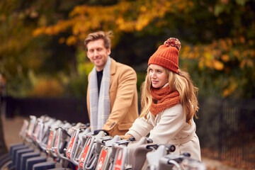 Couple Hiring Bikes As Green Form Of Transport To Get Around City In Autumn Or Fall