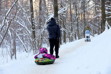 Family leisure in winter park, man rides the child on snow tube. Father with kid, sledding after...