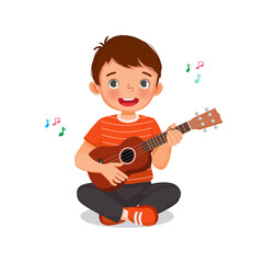 Little boy playing ukulele singing holding a guitar with smiling facial expression