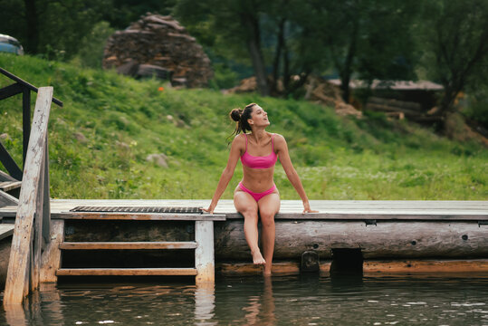 Beautiful woman in bikini on the wooden pier beside a water