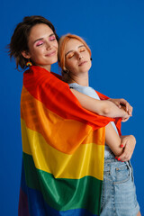 Obraz premium White lesbian couple hugging while posing with rainbow flag