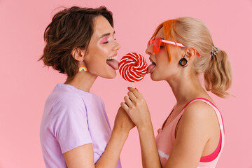 White lesbian couple holding and licking lollipop together