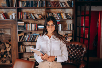 Young woman with documents in hands on the background of a bookshelf