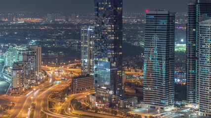 Fototapeta na wymiar JLT skyscrapers near Sheikh Zayed Road aerial night timelapse. Residential buildings and villas behind