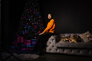 Obraz premium Muslim woman in black hijab near new year tree waiting for celebration of Christmas. Islam religion.