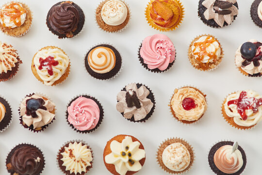 Viele sortierte bunte Cupcakes von oben mit Toppings - Powered by Adobe