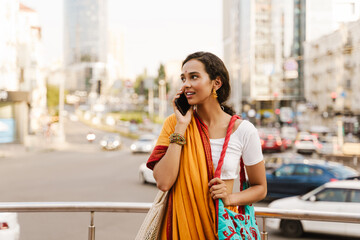 Young indian woman wearing sari talking on cellphone at city street