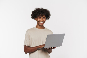 Young black man in t-shirt smiling while using laptop