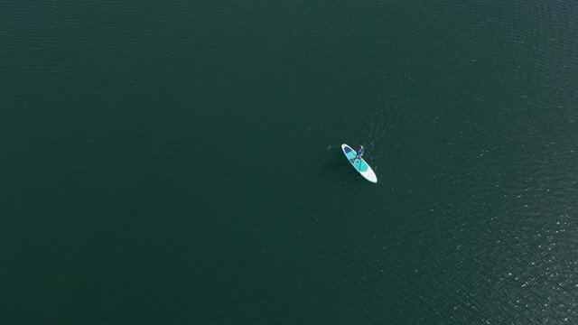 Aerial shot. Young women is having fun. Stand Up Paddling in the sea. SUP. Paddling among debrees of a sunk metal ships