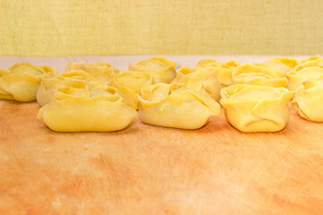 Uncooked manti on cutting board prepared to steaming, selective focus