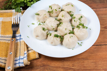 Boiled khinkali on white dish on rustic table
