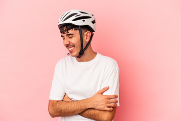 Young mixed race man wearing a helmet bike isolated on pink background laughing and having fun.