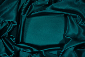 Fototapeta Green silk satin velvet. Wavy soft folds. Smooth. Shiny fabric. Luxurious dark teal background with copy space for design. Table top view. Flat lay. Empty. Template. obraz