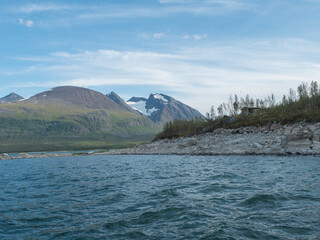 Summer view of over lake Akkajaure to Akka, Ahkka mountain massif with snow and glacier and Anonjalmme saami setllement. Start point of Padjelantaleden hiking trail at in Lapland, Sweden