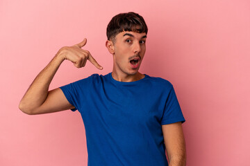 Obraz premium Young mixed race man isolated on pink background person pointing by hand to a shirt copy space, proud and confident