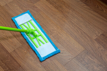 Green mop with blue nozzle washes the laminate. Selective focus. Picture for articles about...