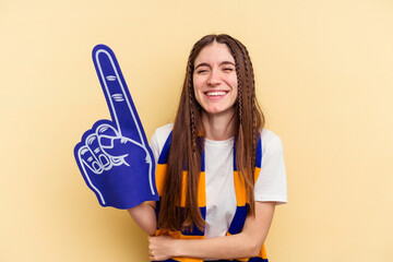 Young sports fan woman isolated on yellow background laughing and having fun.