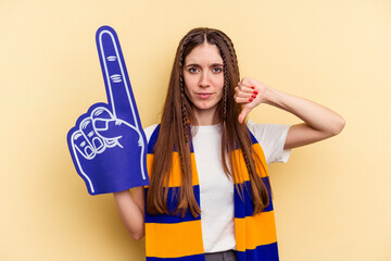 Young sports fan woman isolated on yellow background showing a dislike gesture, thumbs down....