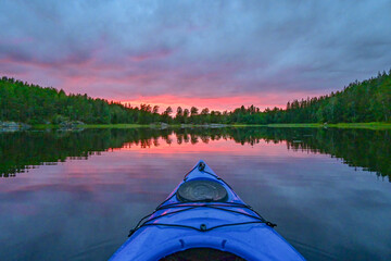 Red impressive sunset over Norwegian lake seen from a kayak POV view