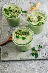 Raw vegan dessert. Matcha green tea chia seed pudding with fresh mint and coconut milk on a gray stone background.