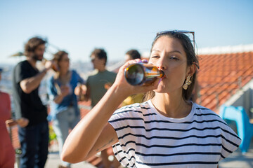 Portrait of woman with dark hair at party. Young Caucasian girl in striped T-shirt looking at...