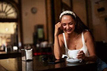 Stylish young woman drinking coffee at cafe. Beautiful girl enjoy in fresh coffee.