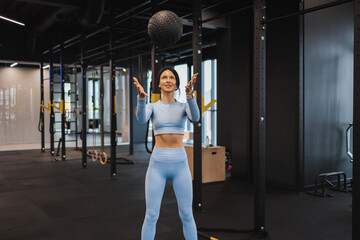 Fitness woman throwing up medical ball in the gym