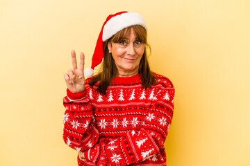 Middle age caucasian woman celebrating Christmas isolated on yellow background showing number two with fingers.