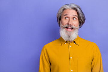 Photo of excited mature man wonder look empty space think idea isolated over violet color background