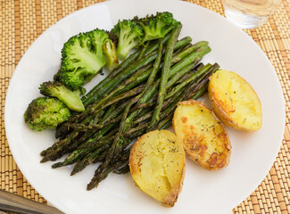 lean dish of cooked fried inflorescences of broccoli, asparagus growth and baked potatoes and Provencal herbs