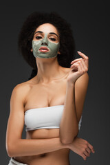young and slim african american woman in clay facial mask posing isolated on grey