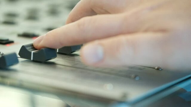 A close up of an audio console with three sliders moved by three fingers. radio station, Israel.