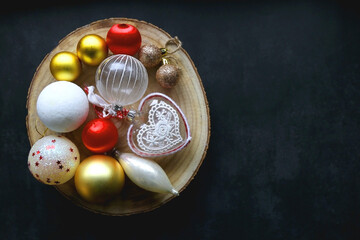 Wooden tray with Christmas ornaments in red, gold and white tones. Dark background, flat lay.