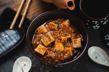 Mapo tofu or chinese dish made of tofu cubes, ground pork and sichuan peppercorns, middle close-up,...