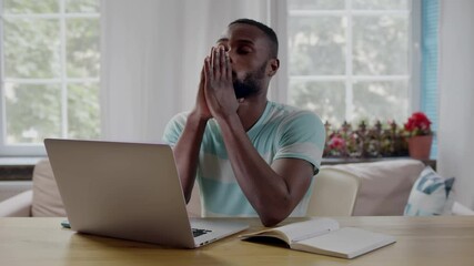 Portrait of young African-American ethnicity man working on laptop feeling stressed. Realtime