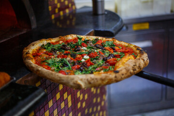 Pizza napoletana con pomodorini, prezzemolo, olive nere, acciughe, aglio e olio