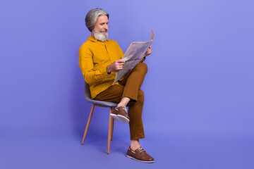 Full length body size view of attractive cheery focused gray-haired man reading press isolated over...