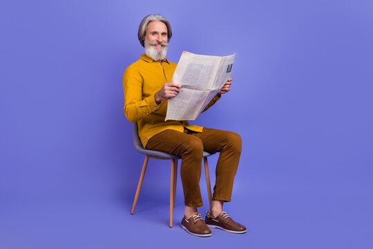 Full length body size view of attractive cheerful gray-haired man reading page isolated over bright violet purple color background