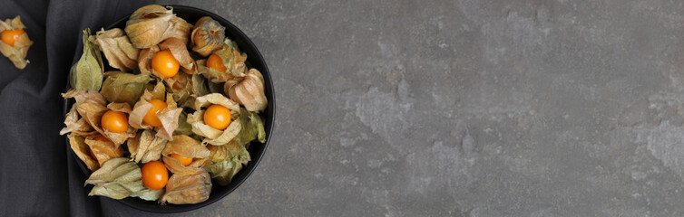 Ripe physalis fruits on grey table, flat lay with space for text. Banner design